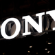 An illuminated Sony logo is suspended on a black background.